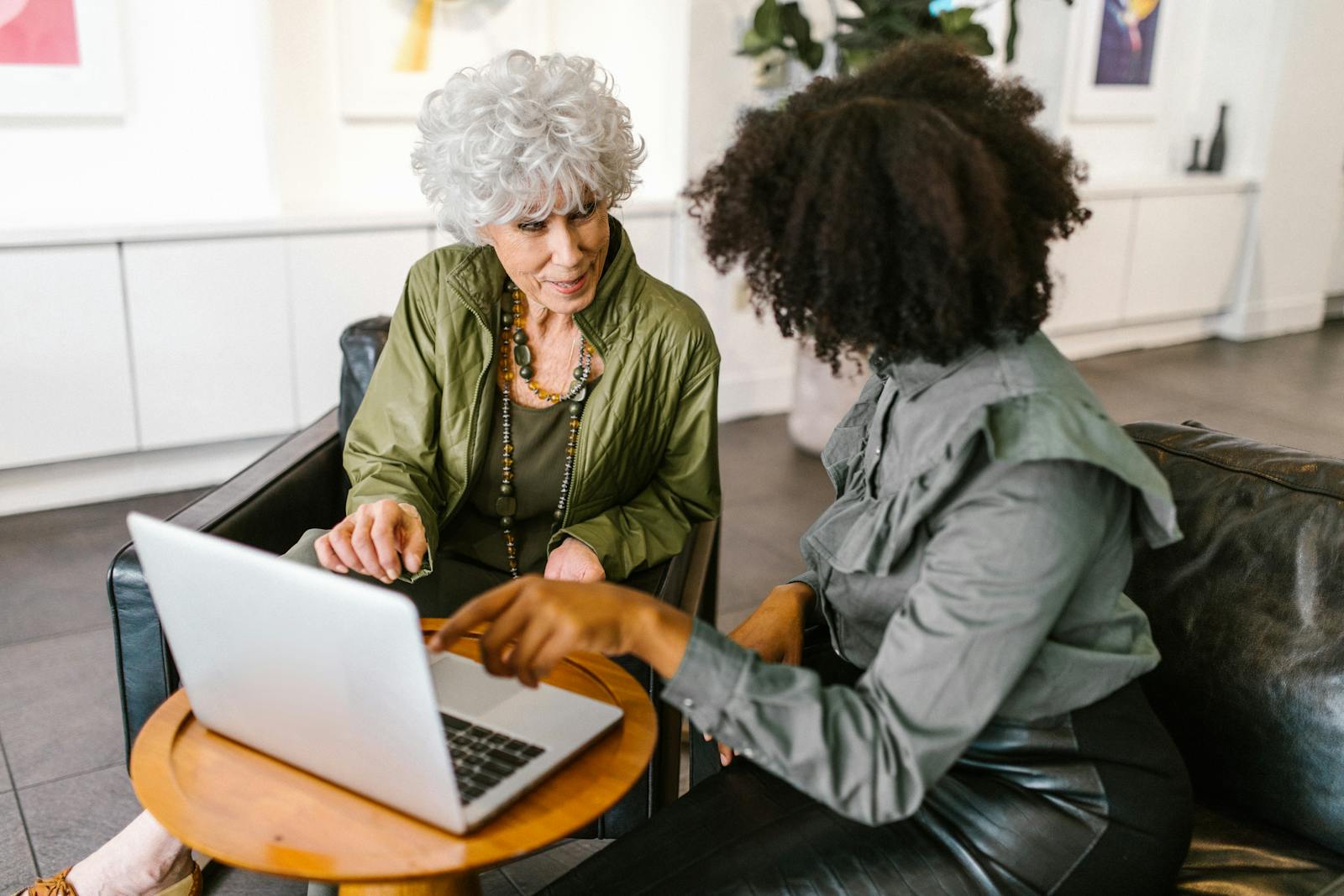 Two women collaborating around a laptop in a warm office setting, representing a thoughtful client onboarding experience